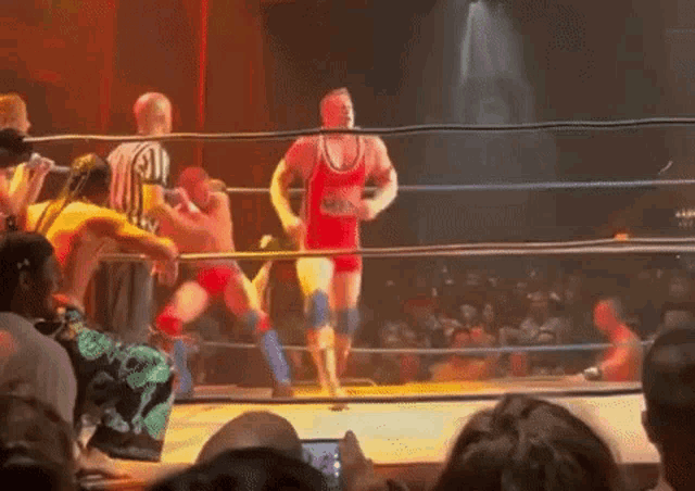 a wrestler wearing a red and yellow outfit with the number 4 on it is in a wrestling ring