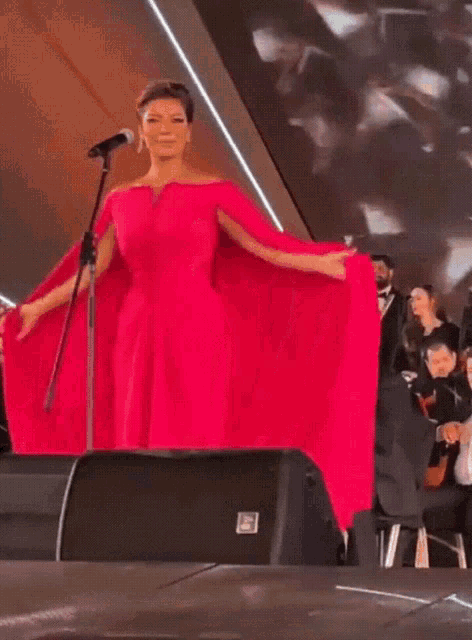 a woman in a red dress is singing into a microphone on a stage