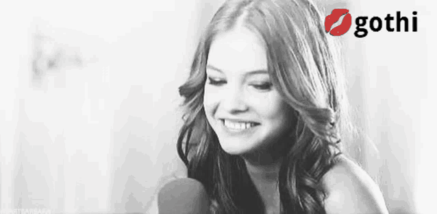 a black and white photo of a woman smiling with a gothi logo in the background .
