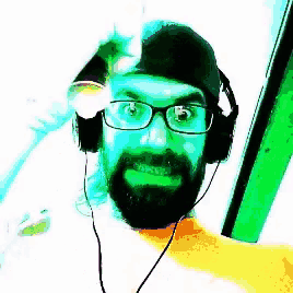 a man with a beard and glasses is wearing headphones and a hat