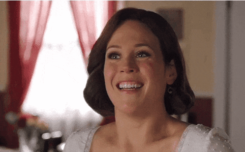 a woman in a white dress is smiling and looking at the camera
