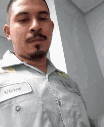 a man with a name tag that says victor is taking a selfie