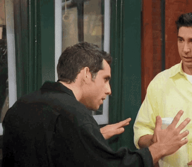 a man in a yellow shirt is talking to another man
