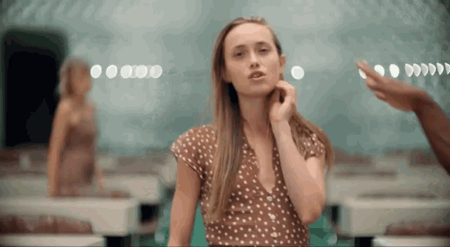 a woman in a brown polka dot dress is standing in a room