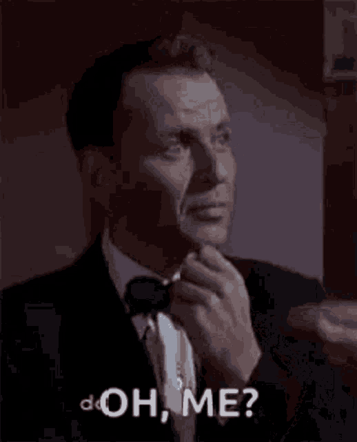 a man in a tuxedo and bow tie is saying `` oh , me ? '' .