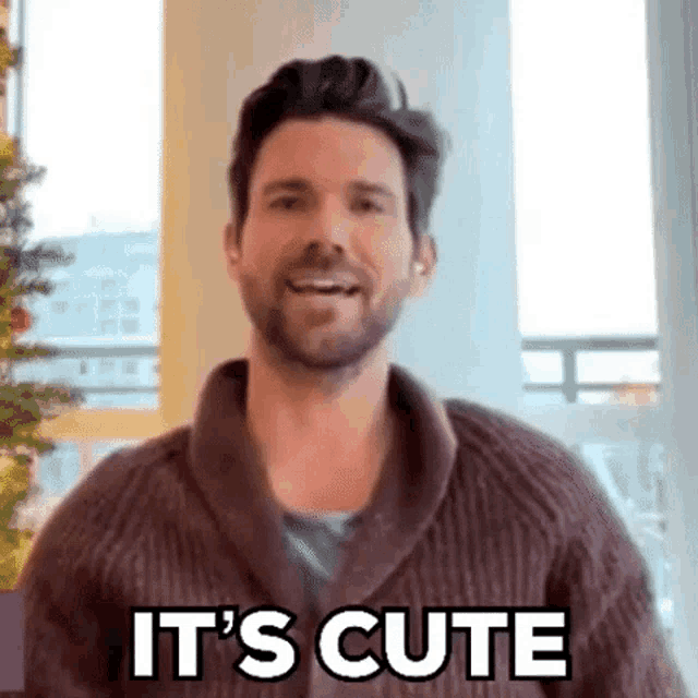 a man in a sweater is smiling and saying it 's cute .