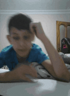 a boy in a blue shirt is laying on a table