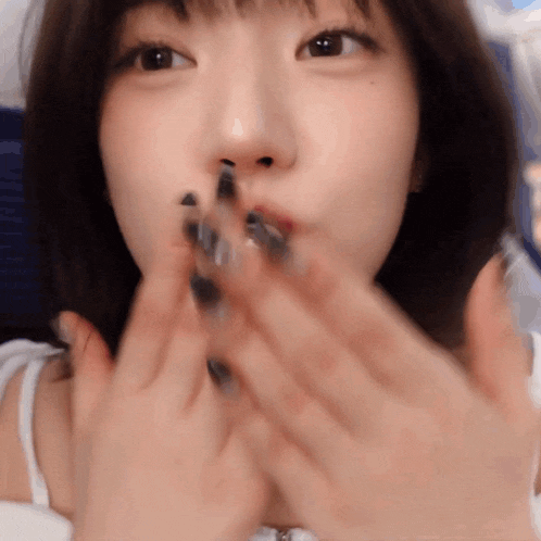 a woman with black nails is blowing a kiss with her hands
