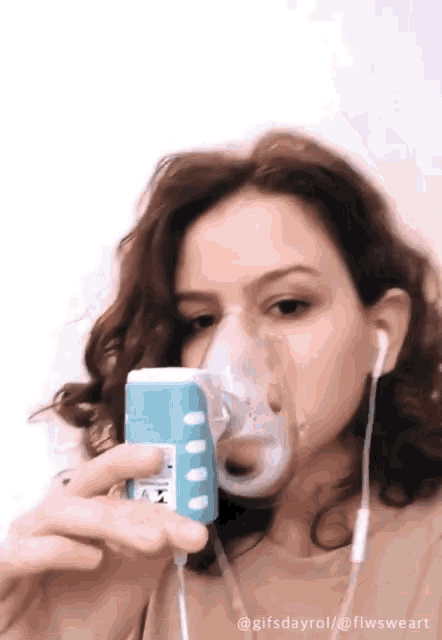 a woman is wearing an oxygen mask and taking a picture of herself