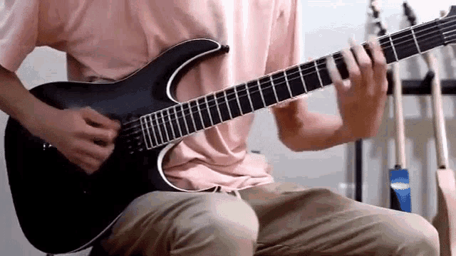 a man in a pink shirt is playing a guitar