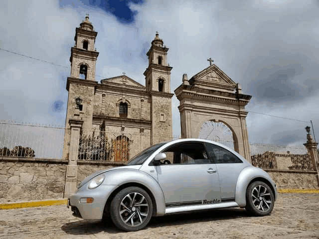 a silver beetle car parked in front of a church