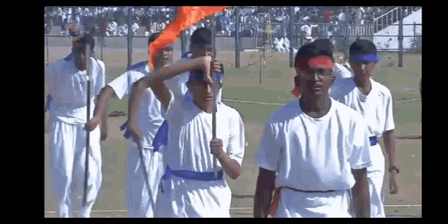 a group of young men in white shirts are marching in a field