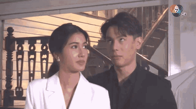 a man and a woman are standing next to each other in front of a staircase .
