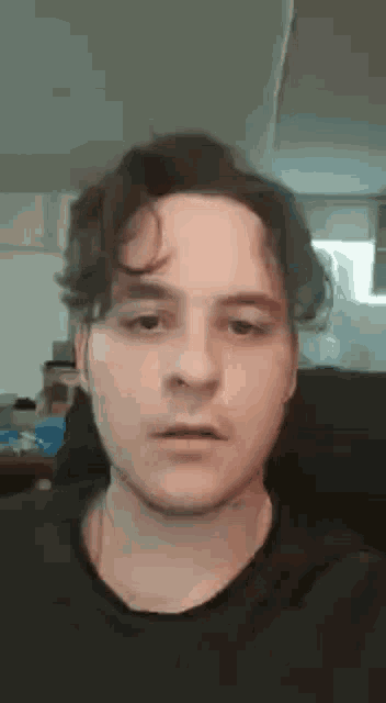 a close up of a man 's face with a black shirt on making a funny face .