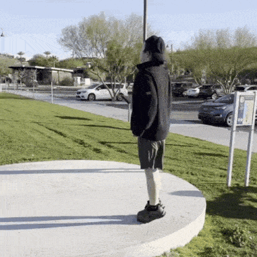 a person standing on a concrete circle in front of a parking lot with a sign that says parking only