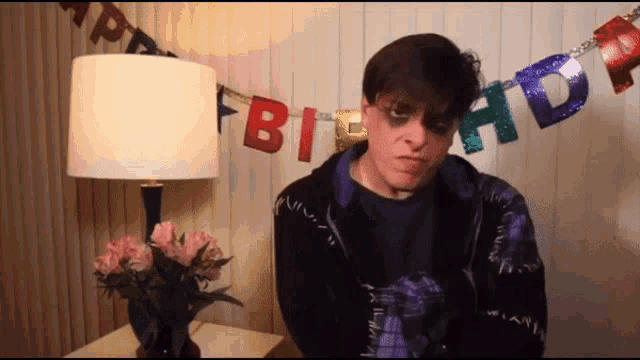a man stands in front of a birthday banner