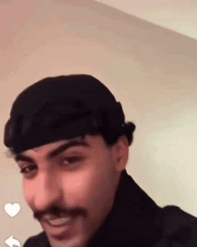a man with a mustache wearing a black hat and smiling