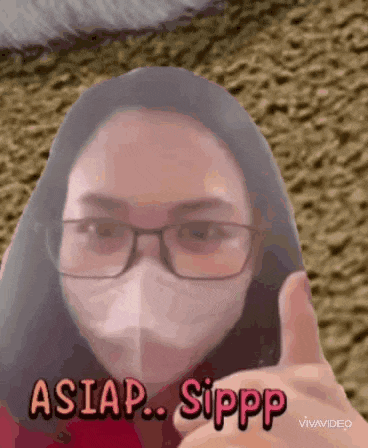 a woman wearing a mask and glasses is giving a thumbs up sign .