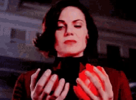 a woman is holding a red object in her hands