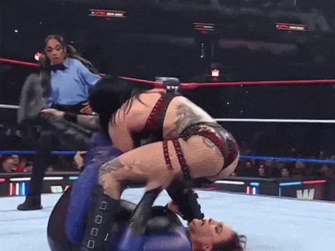 two women are wrestling in a ring and one of them has a tattoo on her back