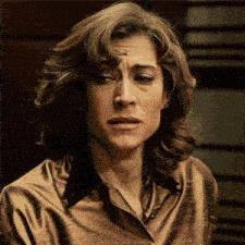 a close up of a woman 's face with a brown shirt on