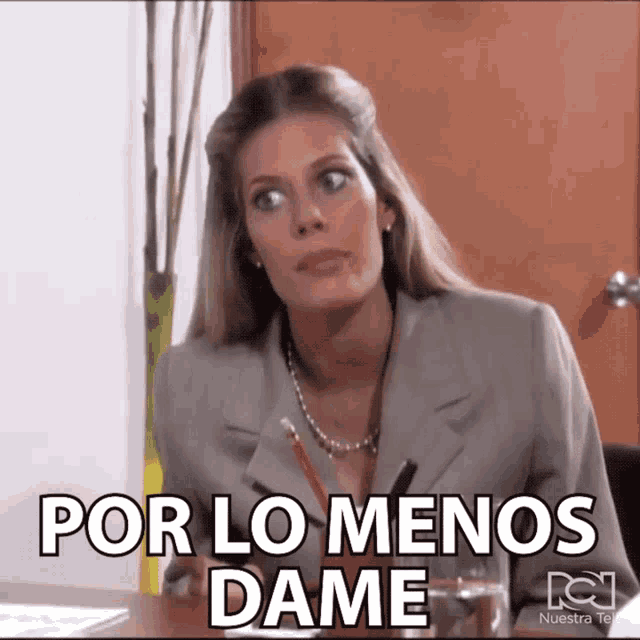a woman sitting at a desk with the words por lo menos dame written on her face