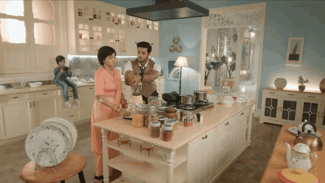 a man and woman cooking in a kitchen with a boy sitting on a table