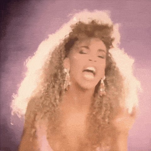 a woman with curly hair is wearing earrings and making a funny face .