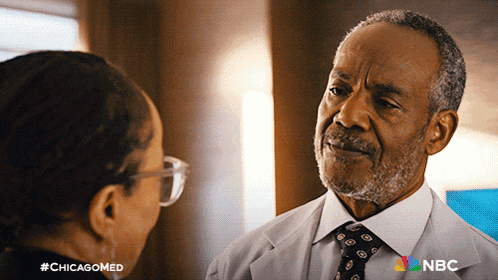 a man in a white coat and tie is talking to a woman in glasses with #chicagomed written on the bottom