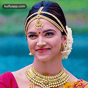 a close up of a woman wearing a necklace and a headpiece smiling .