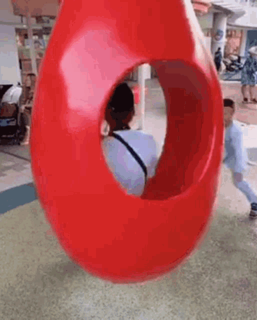 a woman and a child are playing on a red balloon swing .