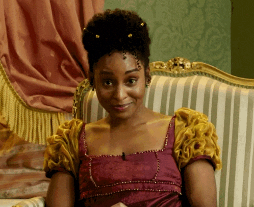 a woman in a purple and yellow dress sits on a striped chair