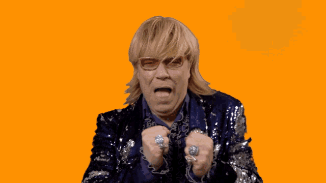 a man in a sequined jacket with rings on his fingers is screaming
