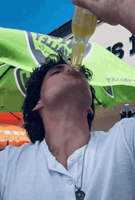 a man drinking from a bottle under an umbrella that says y3jay