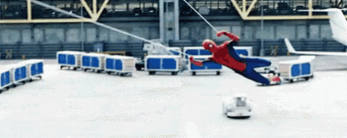 a man in a spiderman costume is flying through the air in front of a plane .