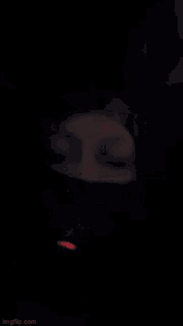 a person is smoking a cigarette in the dark and a red light is shining in the background .