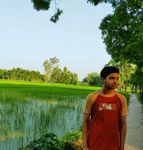a young man wearing a shirt that says we stands in front of a lush green field