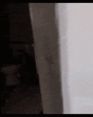 a person is standing in a dark room in front of a white wall .
