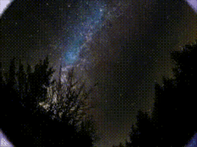 a shooting star is visible in the night sky above trees