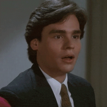 a man in a suit and tie is smiling with his mouth open