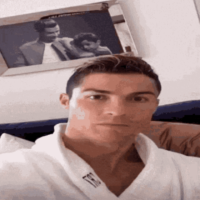 a man in a white robe is taking a selfie in front of a framed picture