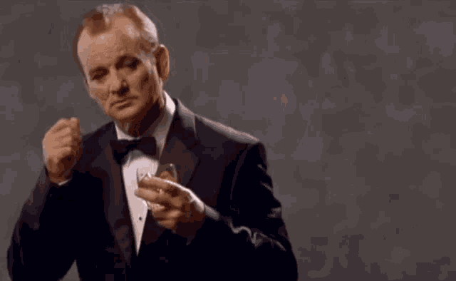 a man in a tuxedo is holding a glass of whiskey and says ring a ding ding in white letters