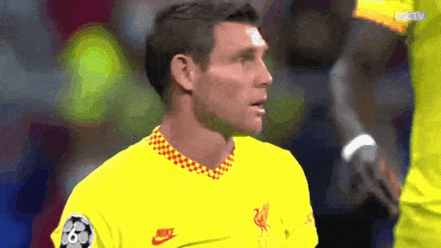 a soccer player wearing a yellow nike shirt looks at the camera