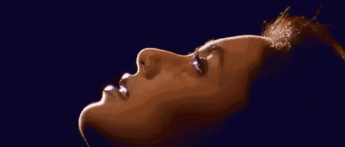 a close up of a woman 's face with a light coming out of her mouth .