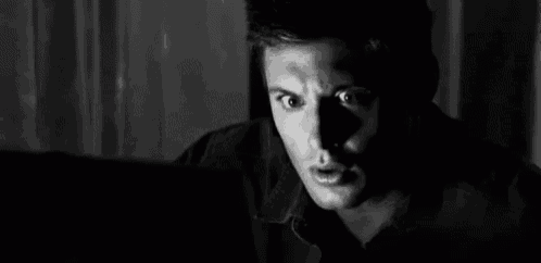 a black and white photo of a man looking at a laptop computer .