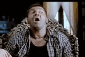 a man in a plaid shirt is sitting on a chair with his mouth open .