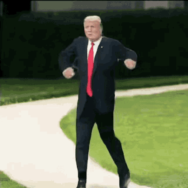 donald trump is wearing a suit and tie and is dancing on a path .
