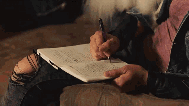 a person writing on a piece of paper with a pen