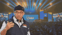 a man wearing glasses and a hat is standing in front of a crowd