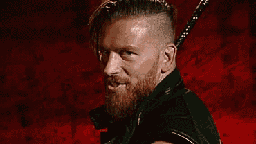 a man with a beard is holding a sword in his hand and smiling .
